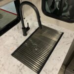 This is a one-piece, slatted sink cover, made of stainless steel and rubber. It's flexible and can be rolled up when not in use, but creates a solid surface when on the sink.
